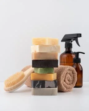 Stack of natural soap bars, wooden body brush, towel, and spray bottle in min Stock Photos