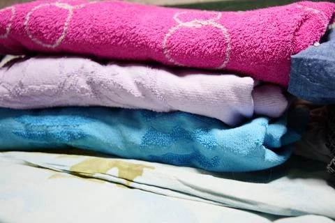 A stack of neatly folded terry cloth towels in vibrant pink, soft lavender,.. Stock Photos