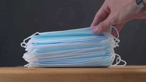 From a stack of new clean medical masks one by one is taken one at a time Stock Footage 162544511