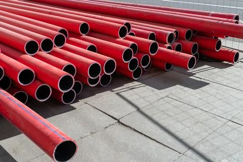 Stack of new, red, plastic, even, long pipelines. PE, HDPE tubes. Stock Photos
