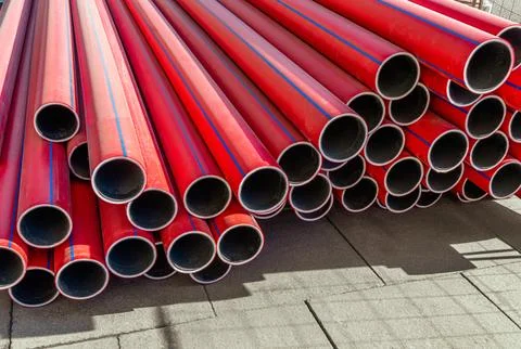 Stack of new, red, plastic, even, long pipelines. PE, HDPE tubes. Stock Photos