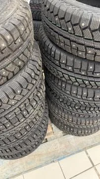 Stack of new winter tires with visible studs in an outdoor setting for auto.. 스톡 사진