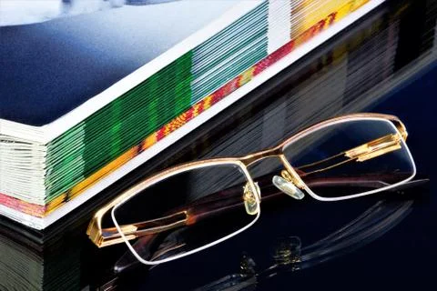A stack of Newspapers and reading glasses on the table. Stock Photos
