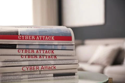 Stack of newspapers with headlines CYBER ATTACK on table indoors, closeup Stock Photos