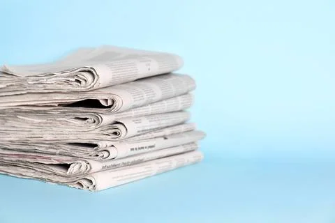 Stack of newspapers on light blue background, space for text Foto stock
