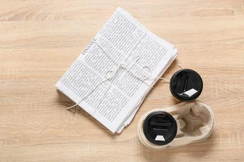 Stack of newspapers tied with string and two takeaway coffee cups on wooden t Foto stock