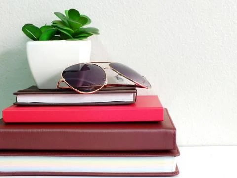Stack of notebook with artificial of plant and sunglasses Stock Photos