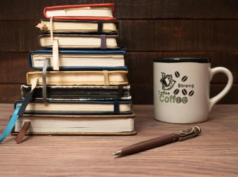 A stack of notebooks and a cup of coffee on a wooden table Stock Photos