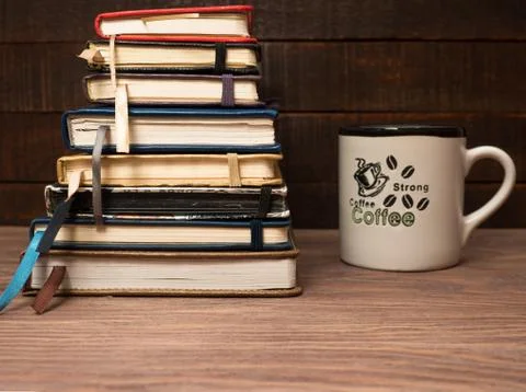A stack of notebooks and a cup of coffee on a wooden table Stock Photos