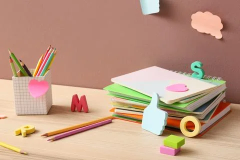 Stack of notebooks with colorful pencils and decorative letters on desk 스톡 사진