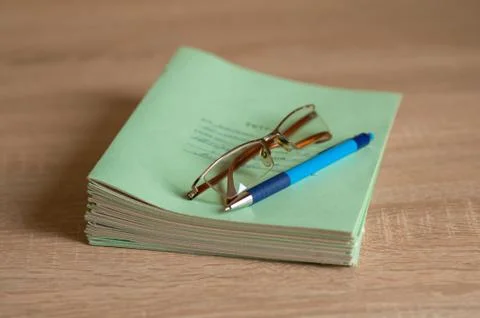 Stack of notebooks, pen and glasses are on the table Stock Photos