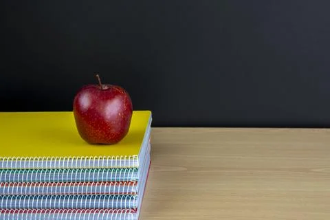 Stack of notebooks with red apple and clean blackboard Stock Photos