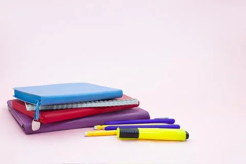 Stack of notepads with pen and marker on pink table. Back to school Stock Photos