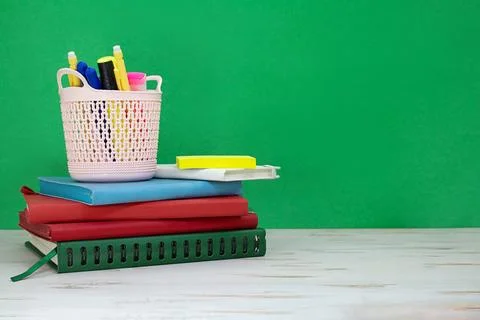 Stack of notepads with pencil case of markers on white table. Green board Stock Photos