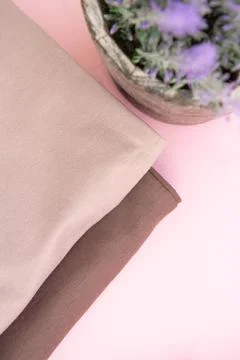 Stack of nude pink clothes and lilac home plant in a pot on pink background Stock Photos