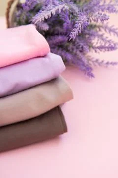 Stack of nude pink clothes and lilac home plant in a pot on pink background Stock Photos