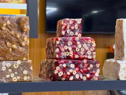 A stack of nut-filled Turkish delights wrapped in plastic. Sweetness, traditi Stock Photos