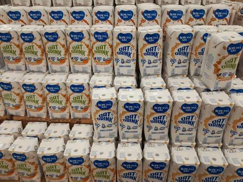 Stack of oat drinks on supermarket shelves. Stock Photos