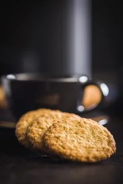 Stack of oatmeal cookies on black table with some placed beside it in a kit.. 스톡 사진