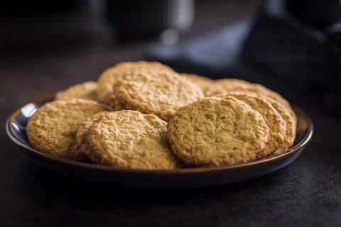 Stack of oatmeal cookies on plate with some placed beside it in a kitchen s.. 스톡 사진