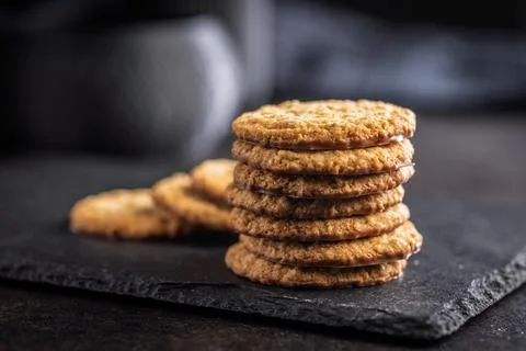 Stack of oatmeal cookies on slate with some placed beside it in a kitchen s.. 스톡 사진