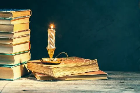 Stack of old antique books and lighten candle Stock Photos