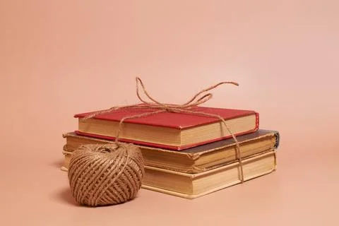 A stack of old battered books tied with jute rope, a coil of jute rope Stock Photos