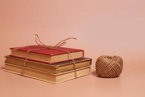 A stack of old battered books tied with jute rope, a coil of jute rope Stock Photos