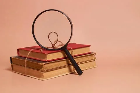 A stack of old battered books tied with a jute rope and a magnifying glass Stock Photos