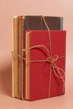 A stack of old battered books tied with a jute rope on a colored background Stock Photos