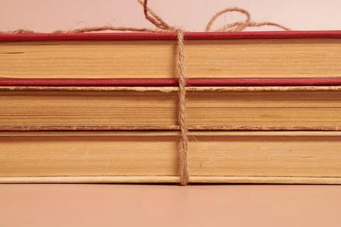 A stack of old battered books tied with a jute rope on a colored background Stock Photos