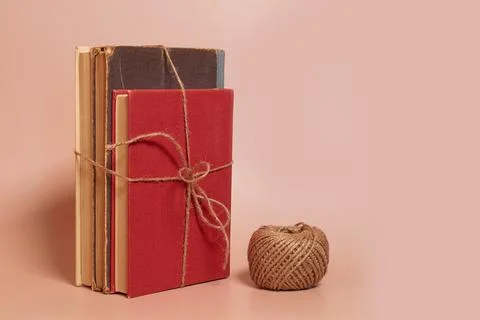 A stack of old battered books tied with jute rope, a coil of jute rope Stock Photos