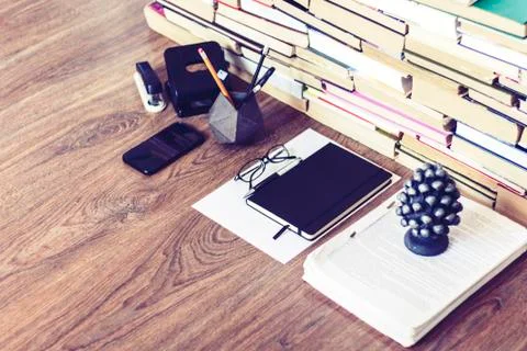 Stack of old book on wooden table, notebook, smartphone, stationery and paper Stock Photos