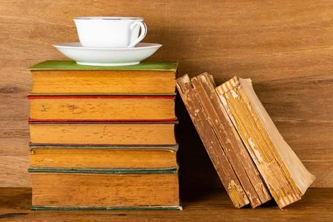 Stack of old books and a cup of coffee on wooden table. Closeup view stack... Stock Photos
