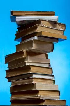 A stack of old books and notebooks on the table on a blue background 库存插图
