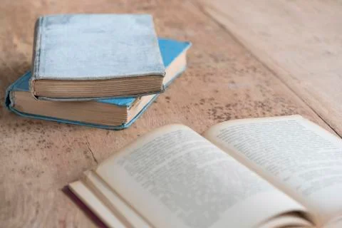 Stack of old books and an opened one on table Stock Photos