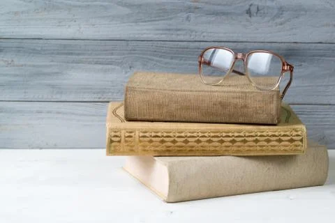 Stack of old books and reading glasses on wooden background Stock Photos