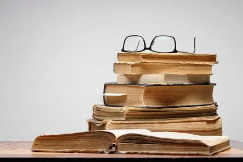 Stack of old books with bookmarks on wooden table. glasses are on top Stock Photos