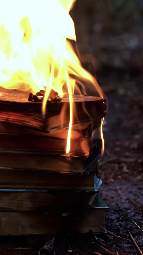 A stack of old books burning outdoors on dirt with intense flames and smoke. Video stock 340483206