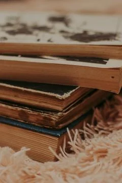 A stack of old books on a cozy fluffy beige blanket. Place for text. Stock-Fotos