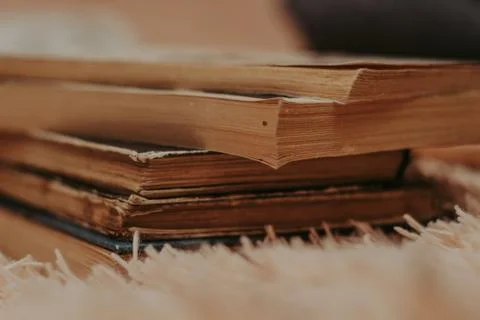 A stack of old books on a cozy fluffy beige blanket. Place for text. Stock-Fotos