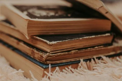 A stack of old books on a cozy fluffy beige blanket. Place for text. Stock Photos