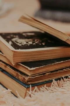A stack of old books on a cozy fluffy beige blanket. Place for text. Stock-Fotos