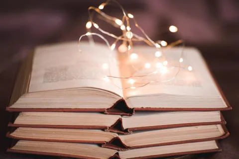 Stack of old books with lights closeup. Home library. Education concept. Stock Photos