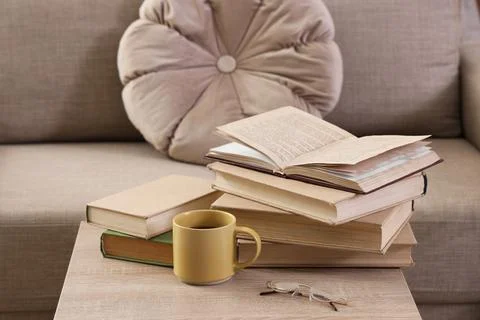 Stack of old books with an open book, coffee mug, and reading glasses on a wo Stock Photos