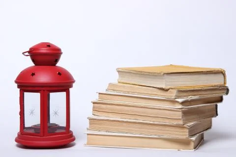 Stack of old books. red lamp with candle Stock Photos