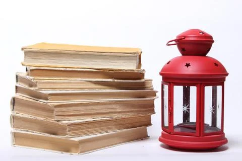 Stack of old books. red lamp with candle Stock Photos