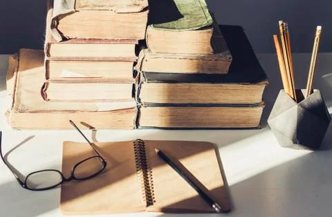 Stack of old books, textbook, glasses and pencils in office background for ed Stock Photos