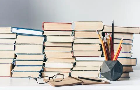Stack of old books, textbook, notebook, glasses and pencils on white table in Stock Photos