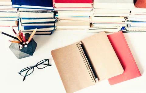 Stack of old books, textbook, notebook, glasses and pencils on white table in Stock Photos